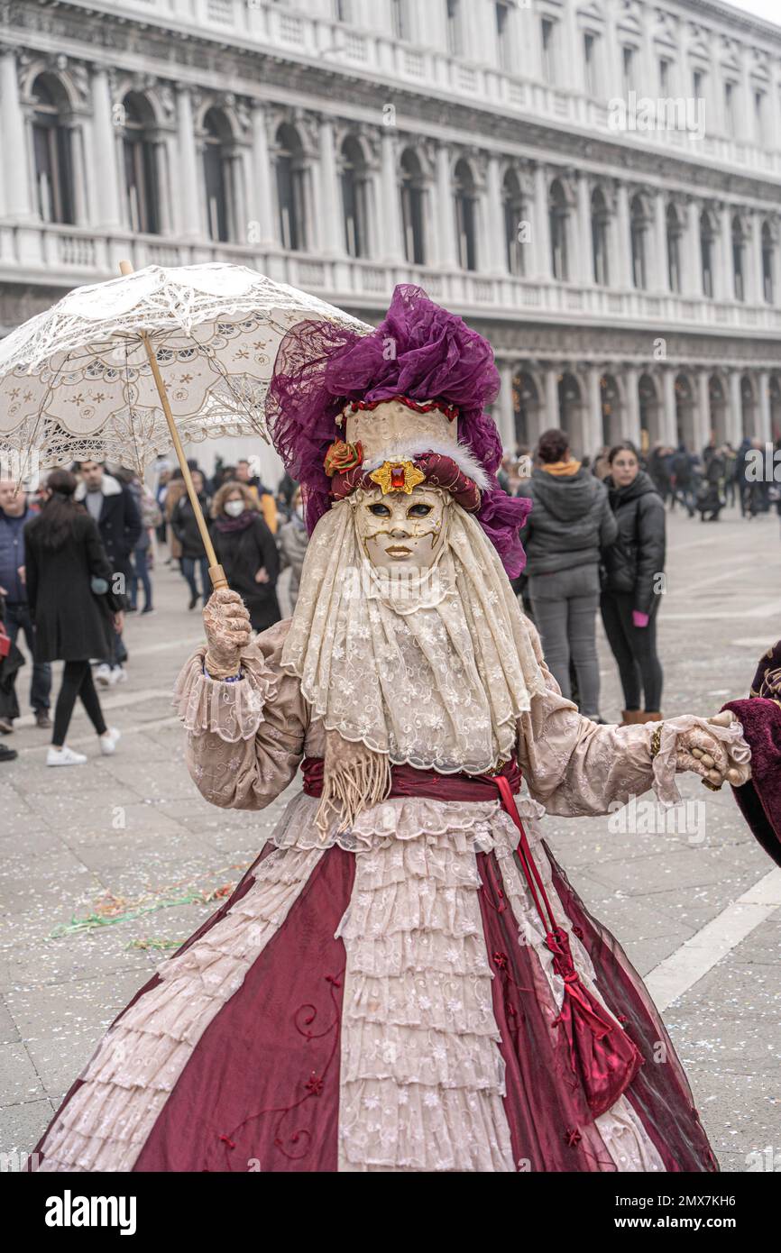 Carnaval de Venise. Une femme en costume de carnaval et masque et chapeau avec plumes et parasol dans sa main au carnaval à Venise, Italie Banque D'Images