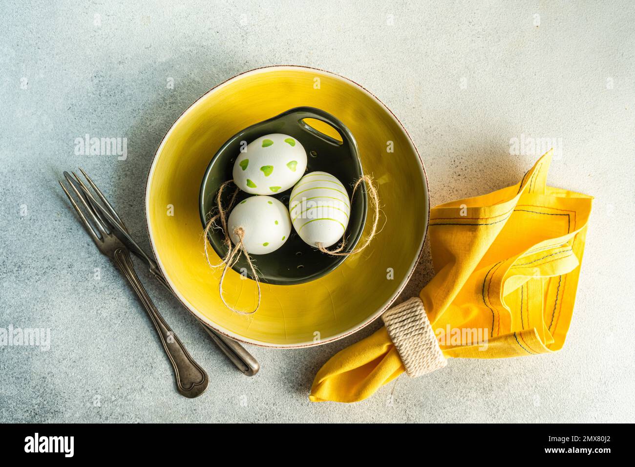 De l'endroit ci-dessus cadre pour le dîner de Pâques avec plaque de céramique jaune et bol avec des œufs de pâques sur fond de béton Banque D'Images