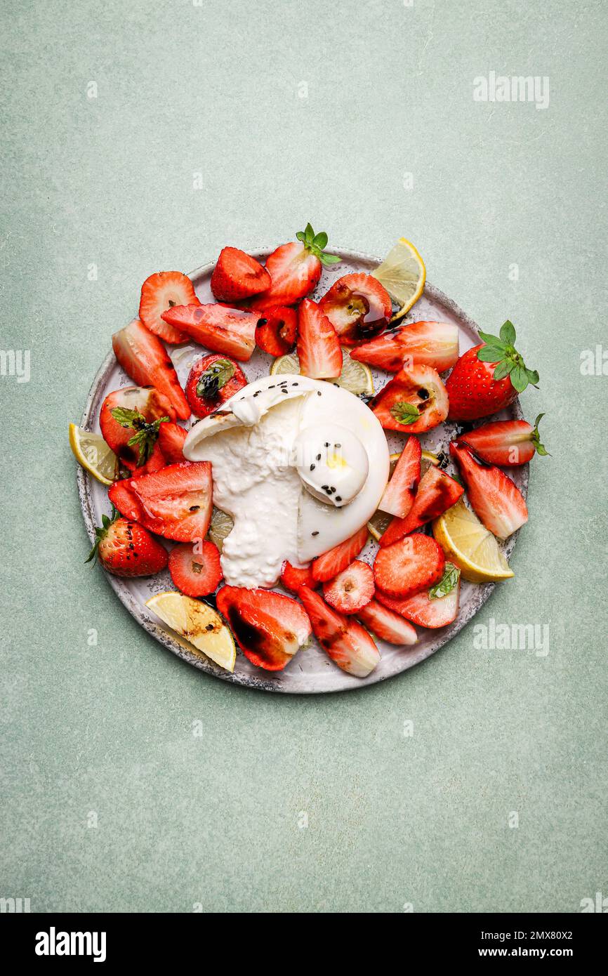 Vue de dessus de fraises fraîches appétissantes et citron servi avec du fromage burrata sur l'assiette Banque D'Images