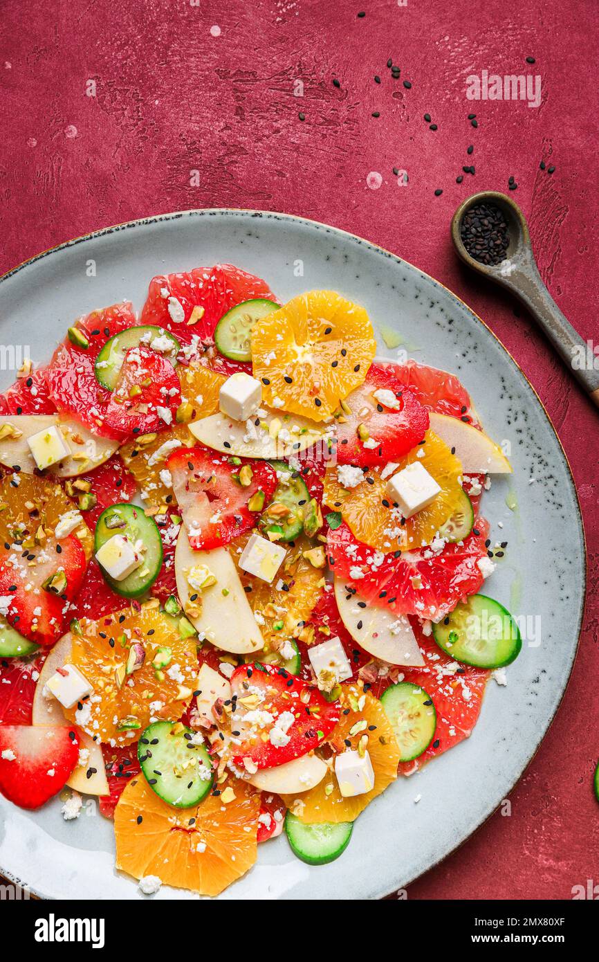 Vue de dessus de salade saine avec des oranges et des fraises et des pommes et des concombres servis avec du fromage et des pistaches sur l'assiette Banque D'Images