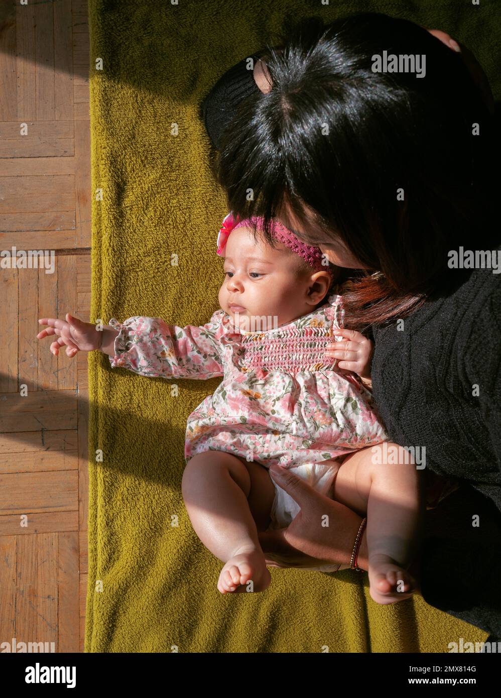 Vue de dessus de la petite mère ethnique allongé sur une couverture avec adorable petit bébé en robe d'été tout en se reposant ensemble à la maison Banque D'Images