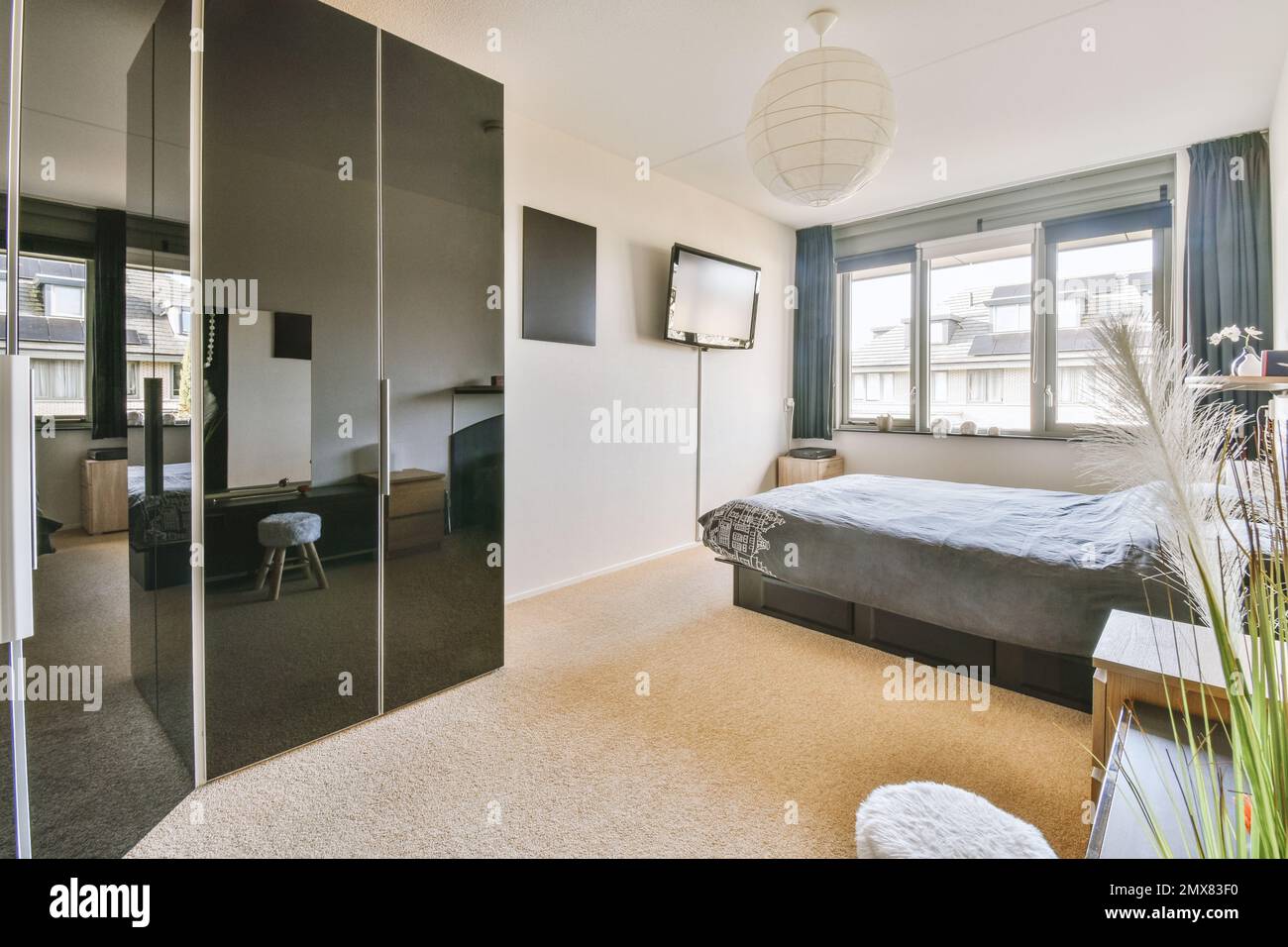 Décoration intérieure de la chambre contemporaine de style minimaliste  meublée avec une armoire à coup d'œil noire et un lit recouvert d'une  couverture grise placée sur la moquette Photo Stock - Alamy