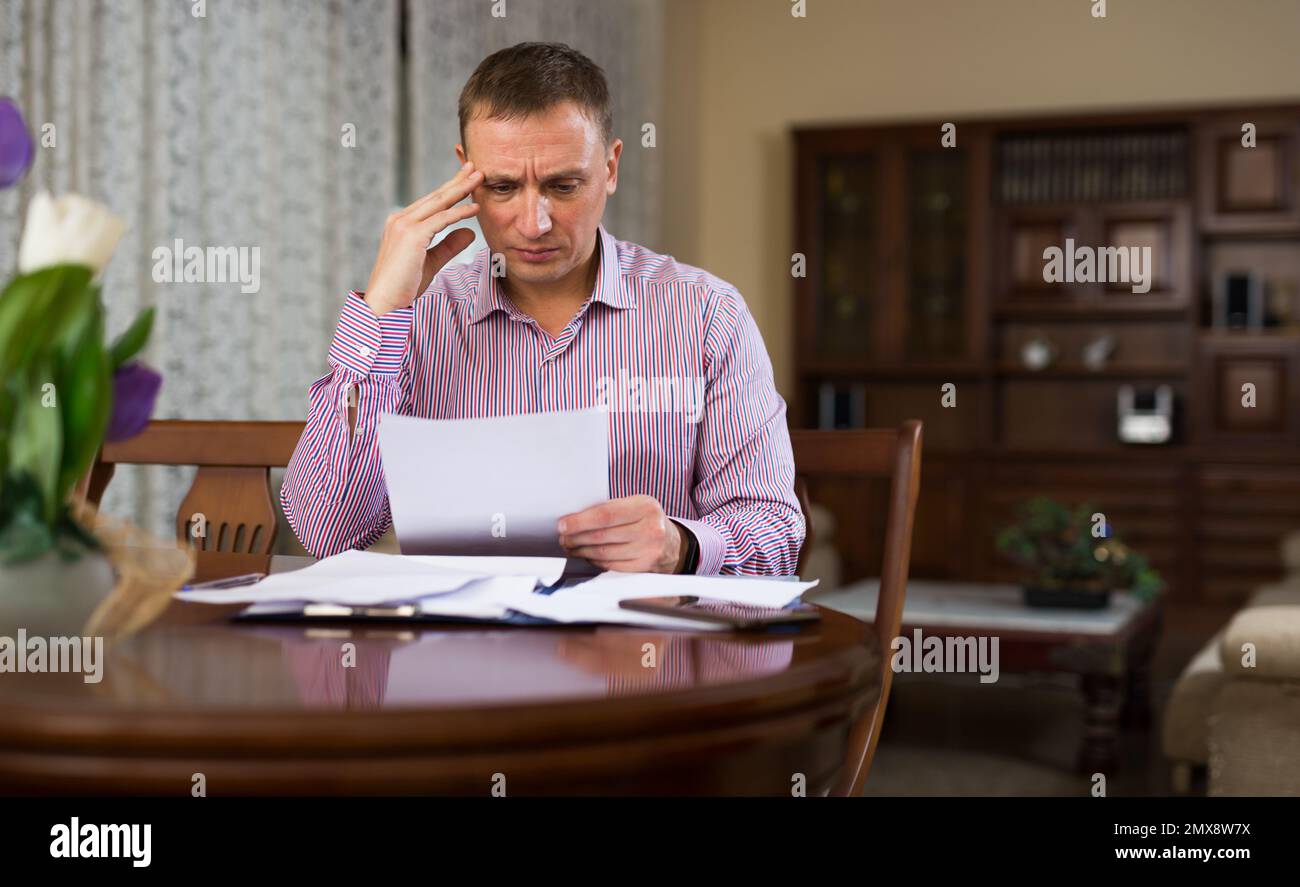 Triste homme frustré à à bout de papier à la table Banque D'Images