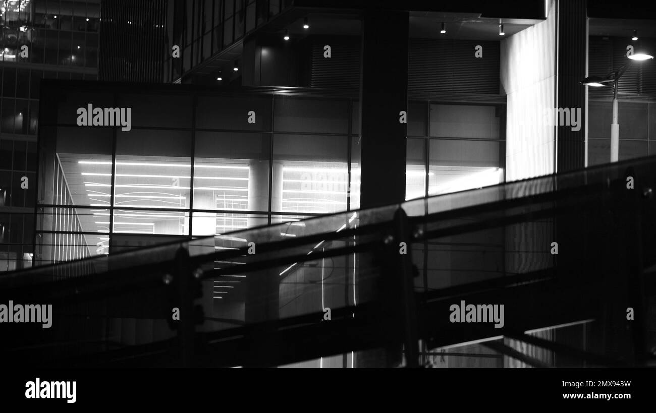 Structure des bureaux fenêtres illuminées la nuit. Éclairage avec architecture en verre design de façade avec réflexion en ville. Noir et blanc. Banque D'Images