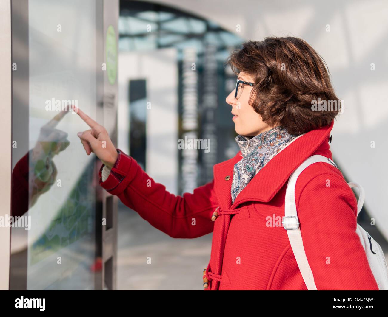 La femme maurique en manteau rouge est l'écran défilant sur l'appareil de navigation électronique d'extérieur. Panneaux électroniques modernes dans les rues pour e-commerce ou tourisme m Banque D'Images