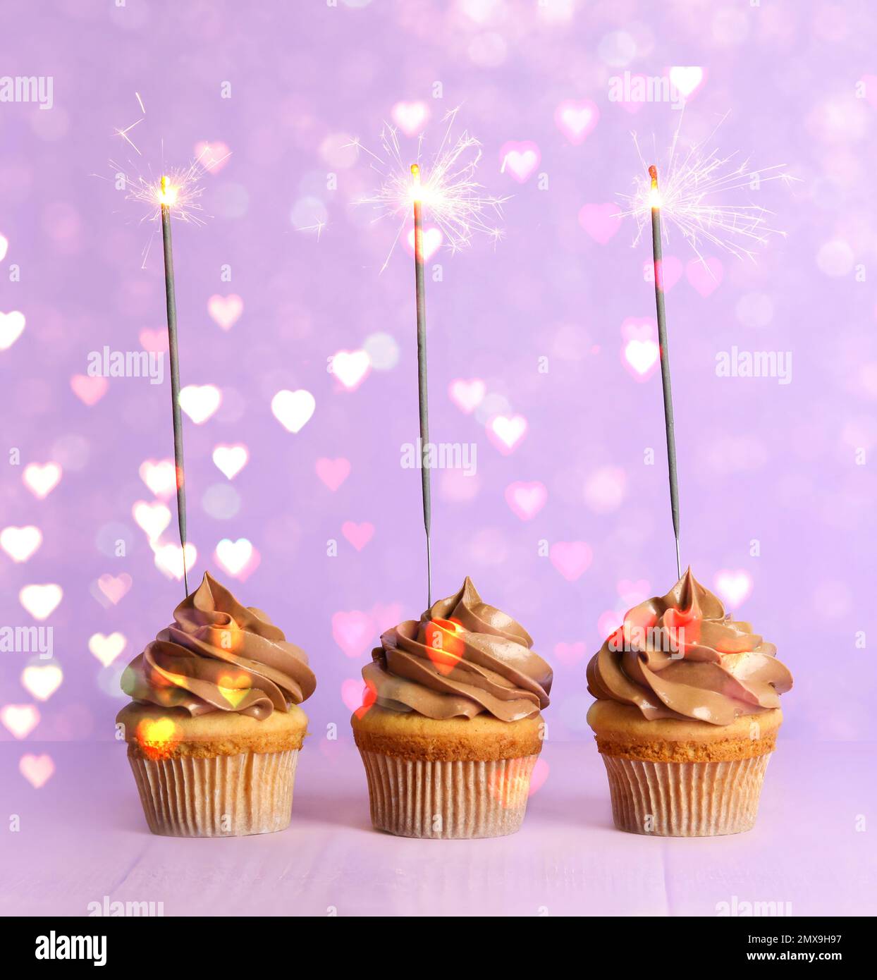 Cupcakes d'anniversaire avec sparkers sur fond violet. Décoration de fête Banque D'Images