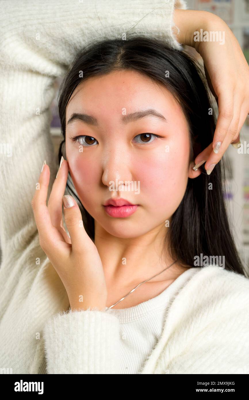 Gros plan portrait de la belle adolescente asiatique avec les mains encadrant le visage Banque D'Images