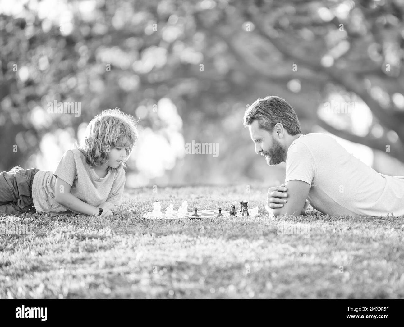 bonne famille de papa et fils enfant jouant aux échecs sur l'herbe verte dans le parc en plein air, génie Banque D'Images