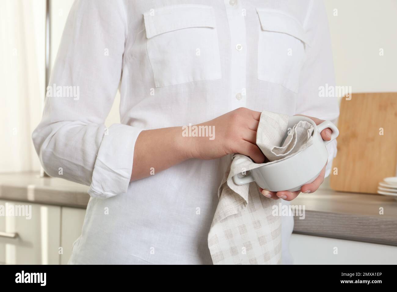 Femme essuyant un bol avec une serviette dans la cuisine, gros plan Banque D'Images