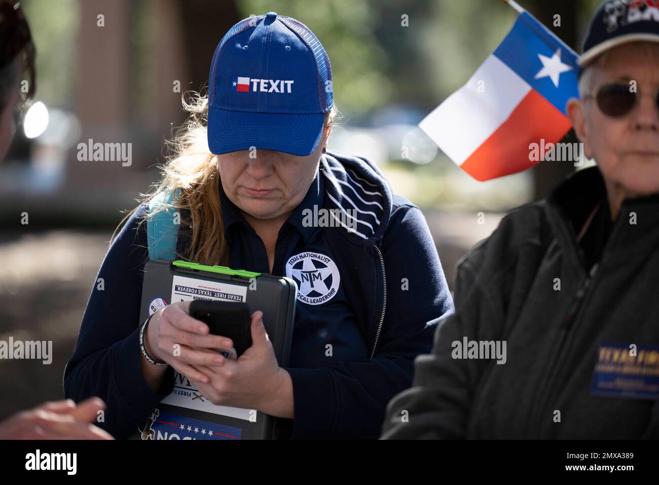 Austin Texas États-Unis, 29 janvier 2023: Une femme portant un chapeau 'Texit' et portant une veste avec le logo du mouvement nationaliste texan vérifie son téléphone cellulaire lors d'un rassemblement à faible participation au Capitole du Texas. Le petit groupe a exhorté les législateurs à faire des plans pour que le statut se séparade des États-Unis. ©Bob Daemmrich Banque D'Images