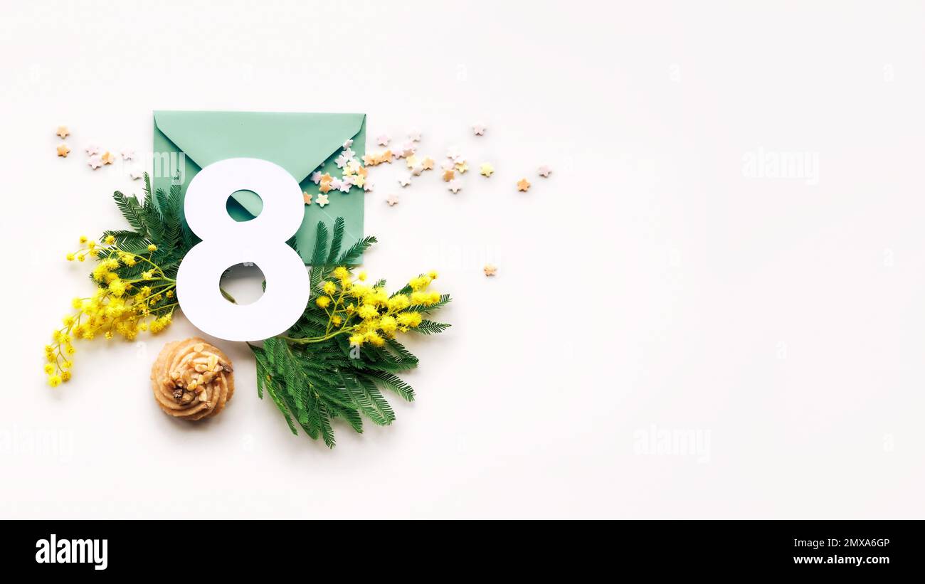 Numéro 8 sur enveloppe papier avec fleurs mimosa fraîches, symbole du printemps. Organisation de la Journée internationale de la femme sur papier blanc, bannière panoramique Banque D'Images