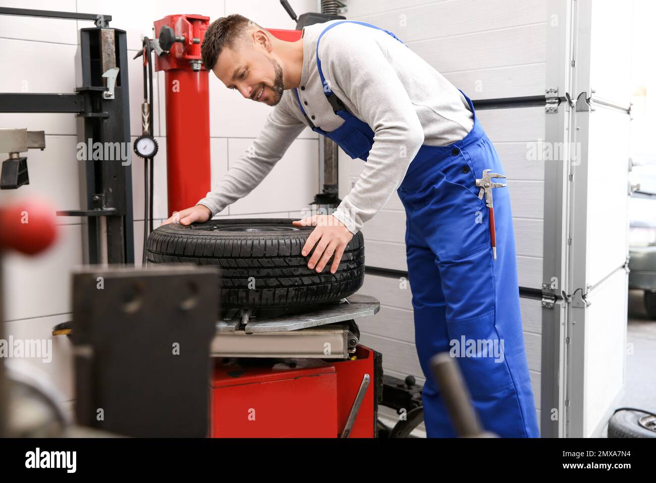 Mécanicien travaillant avec la machine de pose de pneus lors de l'entretien de la voiture Banque D'Images