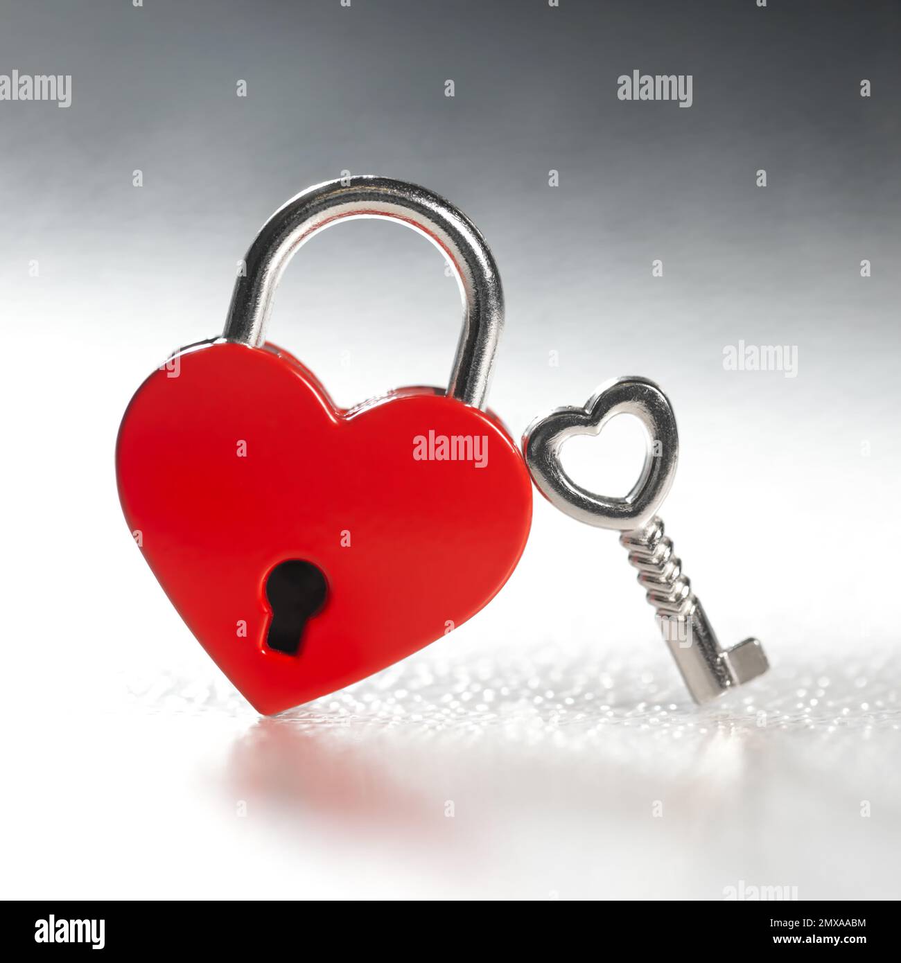 Verrouillez la forme d'un cœur rouge avec une petite clé. L'amour dans le mariage, le mariage, ou le concept de la Saint-Valentin. Banque D'Images