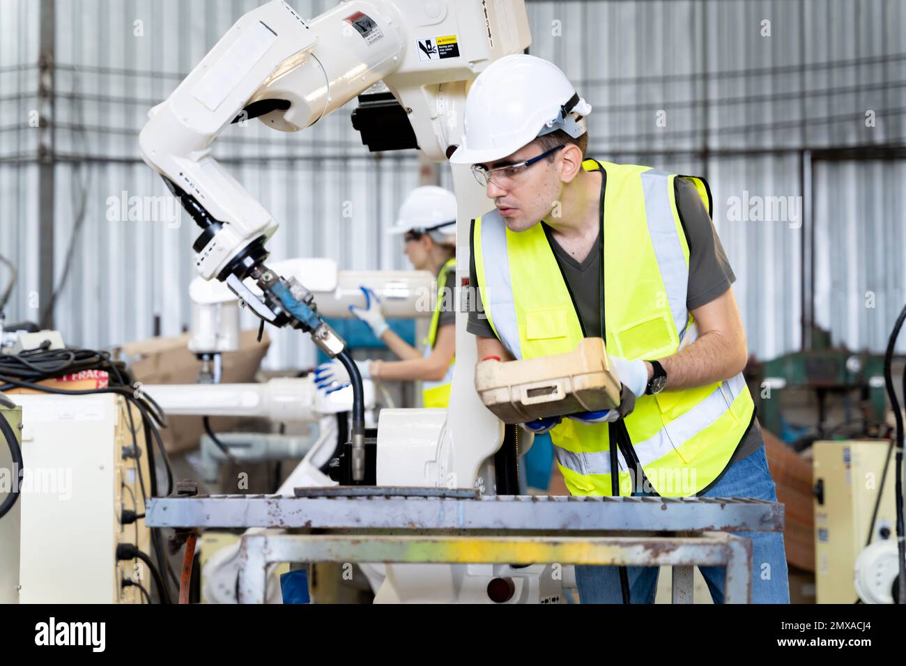 Une équipe d'ingénieurs hommes et femmes se réunit pour inspecter les robots de soudage de l'acier commandés par ordinateur. Planifier les répétitions et l'installation pour l'utilisation. Banque D'Images