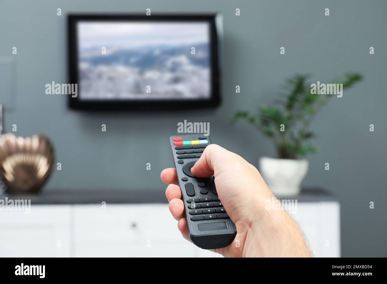 Homme changeant de chaîne sur le téléviseur à l'aide de la télécommande à la maison Banque D'Images