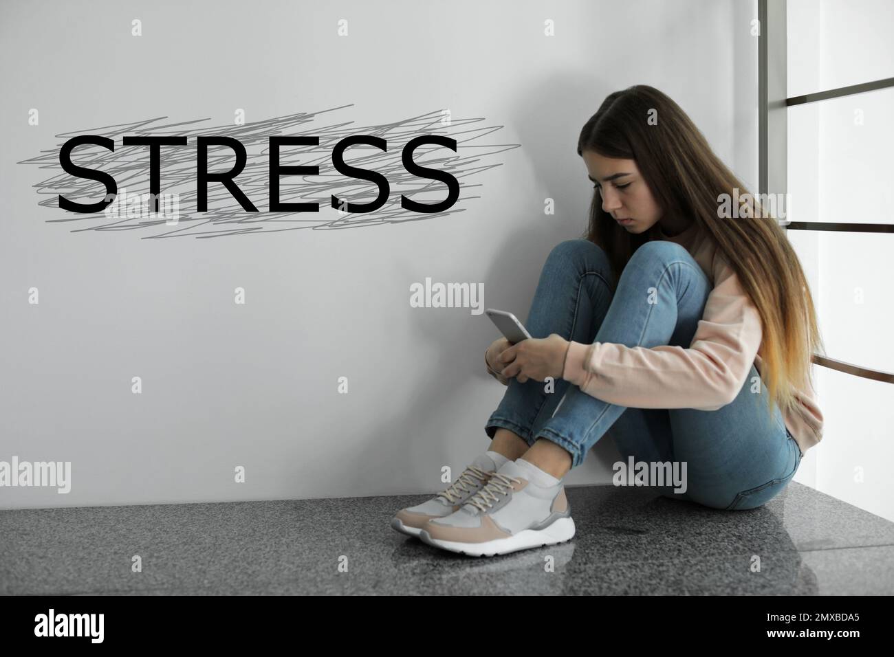 Jeune fille déprimé assise sur le sol à l'intérieur et le stress de mot Banque D'Images