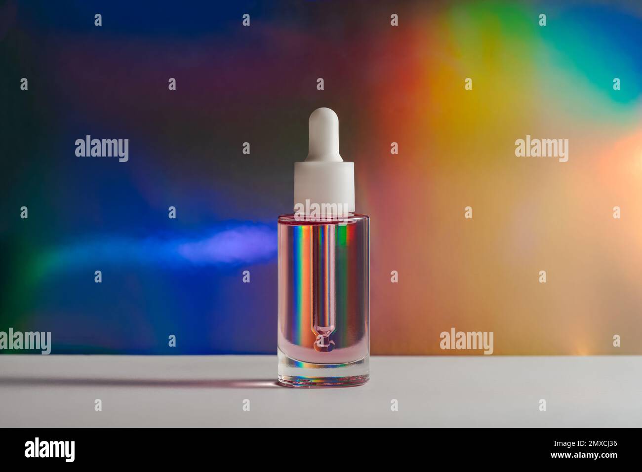 huile rose pour le visage avec flacon compte-gouttes dans un prisme arc-en-ciel. Vue latérale Banque D'Images
