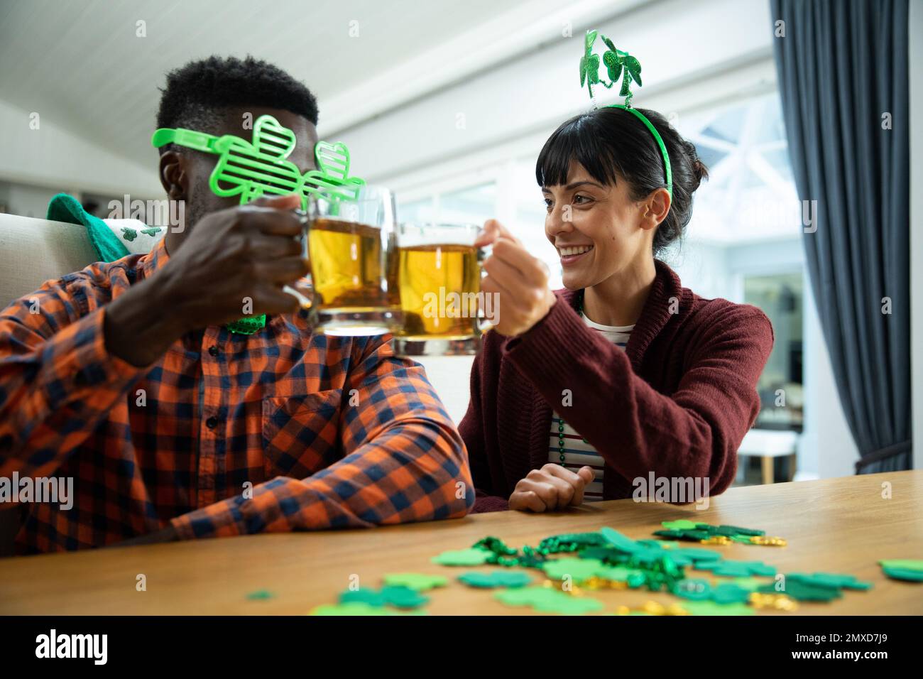 Des amis multiiraciaux qui déguste des tasses de bière tout en appréciant la fête de St patrick à la maison Banque D'Images