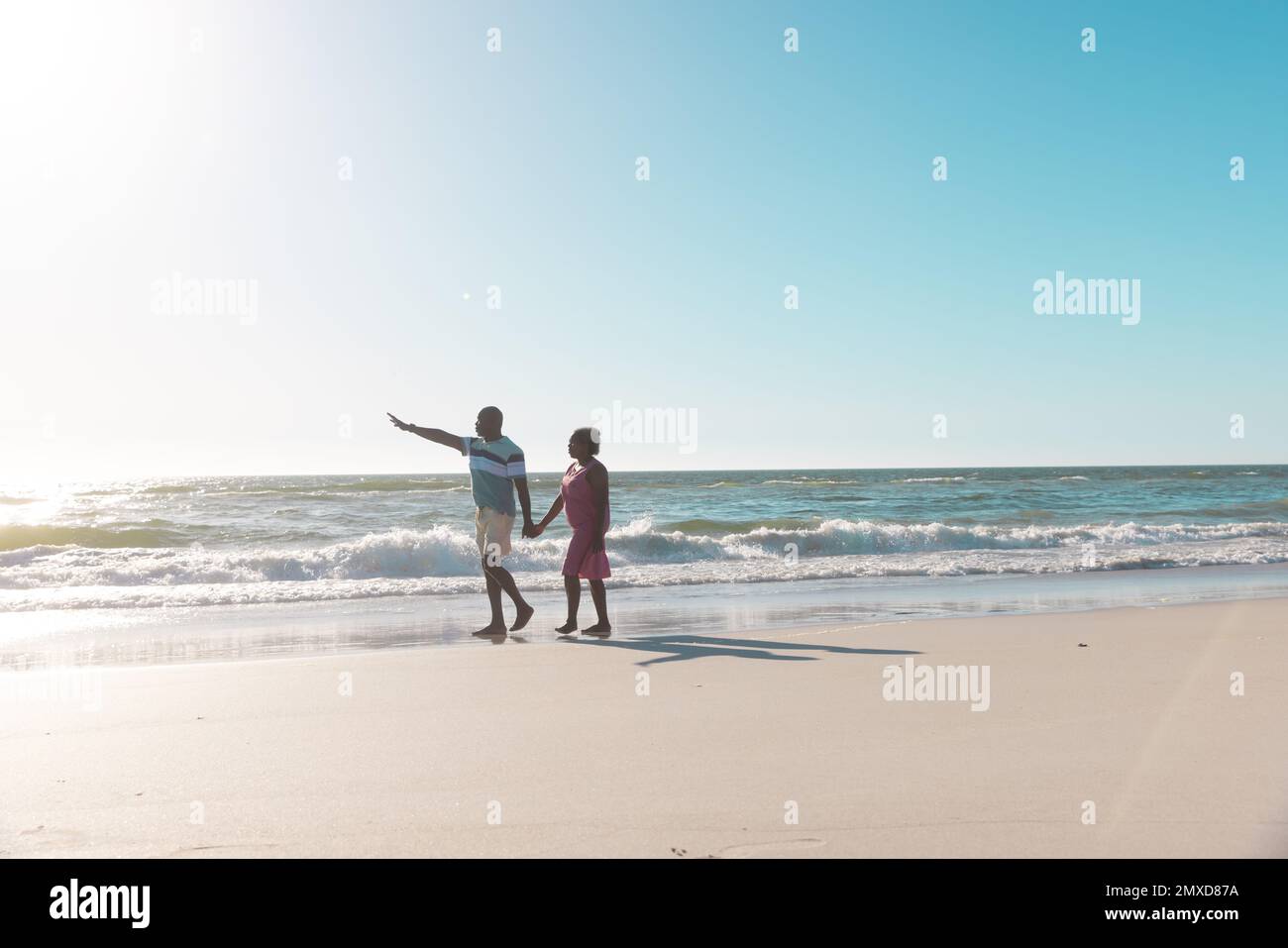 Un couple afro-américain de haut niveau tient les mains et marche sur terre sous un ciel bleu clair en été Banque D'Images