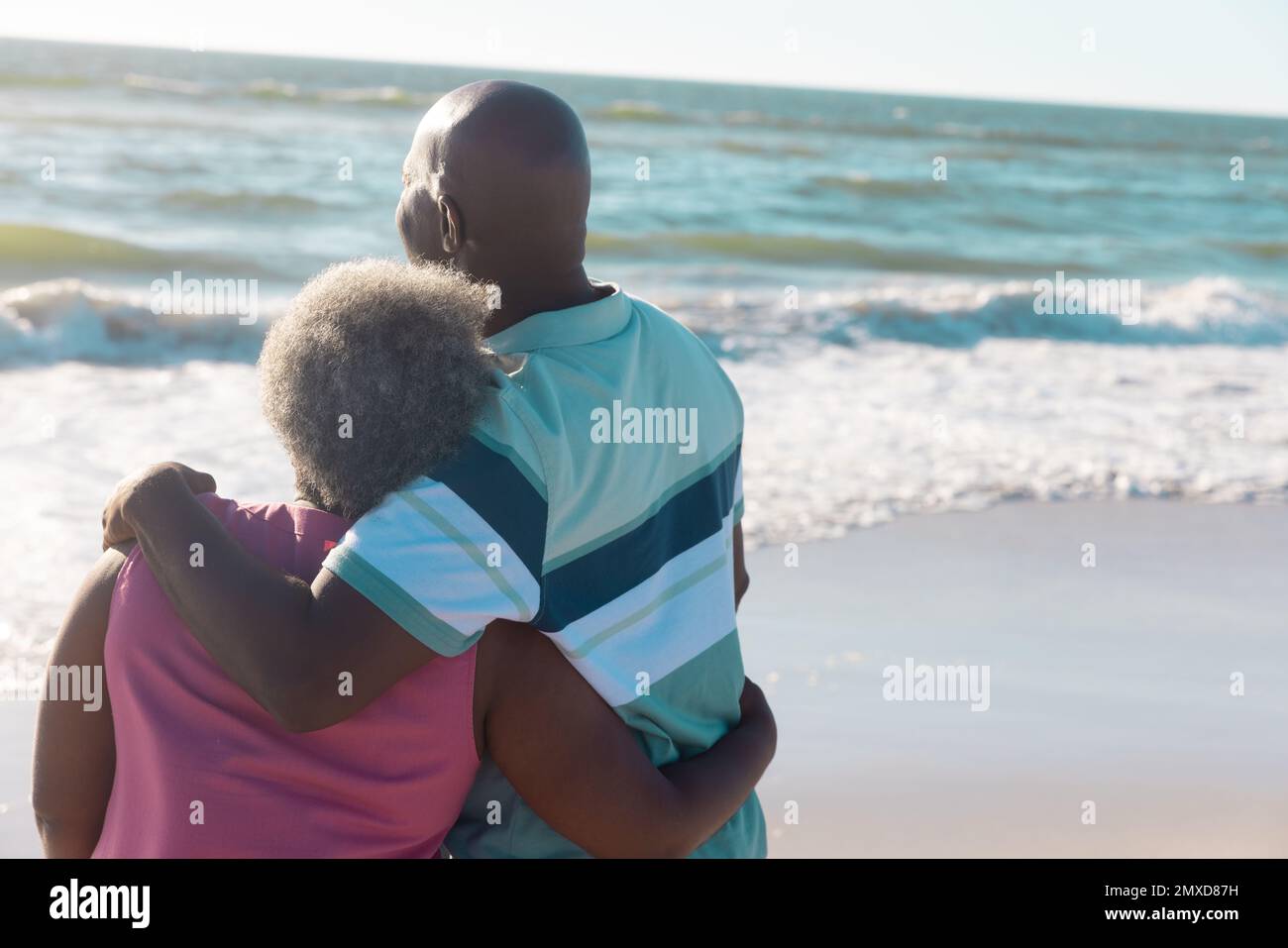 Couple senior afro-américain romantique avec les bras autour de regarder un magnifique paysage marin sous le ciel Banque D'Images