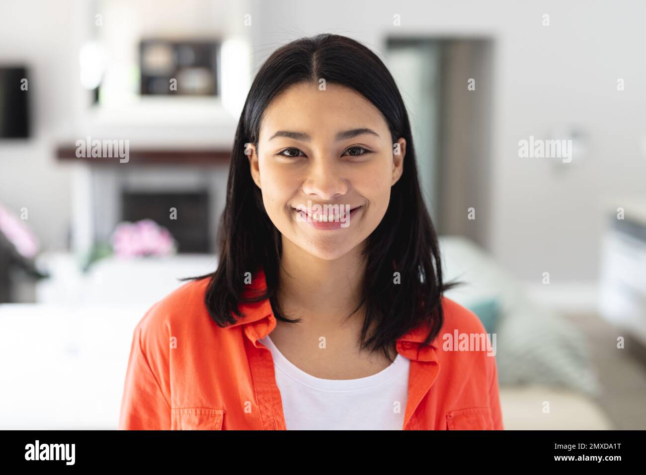 Portrait d'une heureuse femme biraciale souriant dans le salon à la maison, avec espace de copie. Concept de loisirs, de bonheur et de vie domestique. Banque D'Images