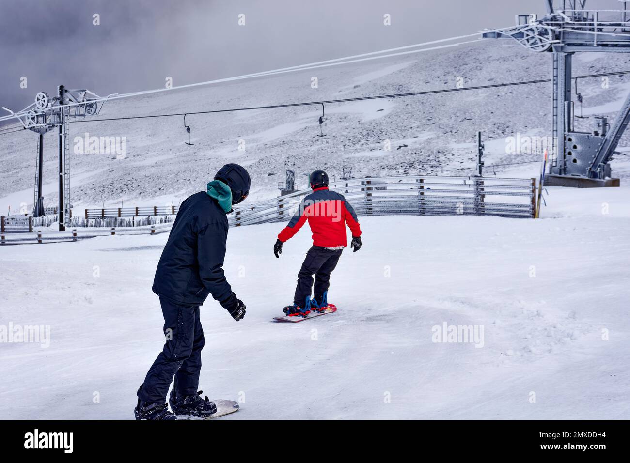Cairngorm Mountain Aviemore Top Station deux snowboarders qui descendent la pente ou courent Banque D'Images