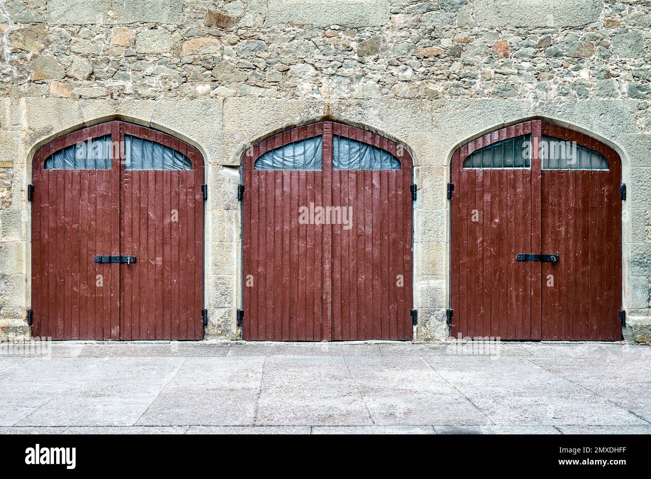 Des portes en bois marron sur un mur entouré de pierres de conception médiévale cachent des choses mystérieuses des visiteurs d'arrivée. Extérieur de la place médiévale Banque D'Images