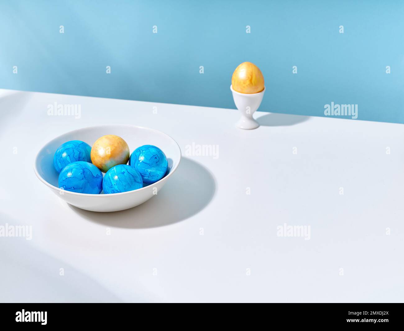 Mise en page créative avec œufs de pâques bleus et dorés sur fond lumineux. Un modèle pour le contenu de fête Banque D'Images