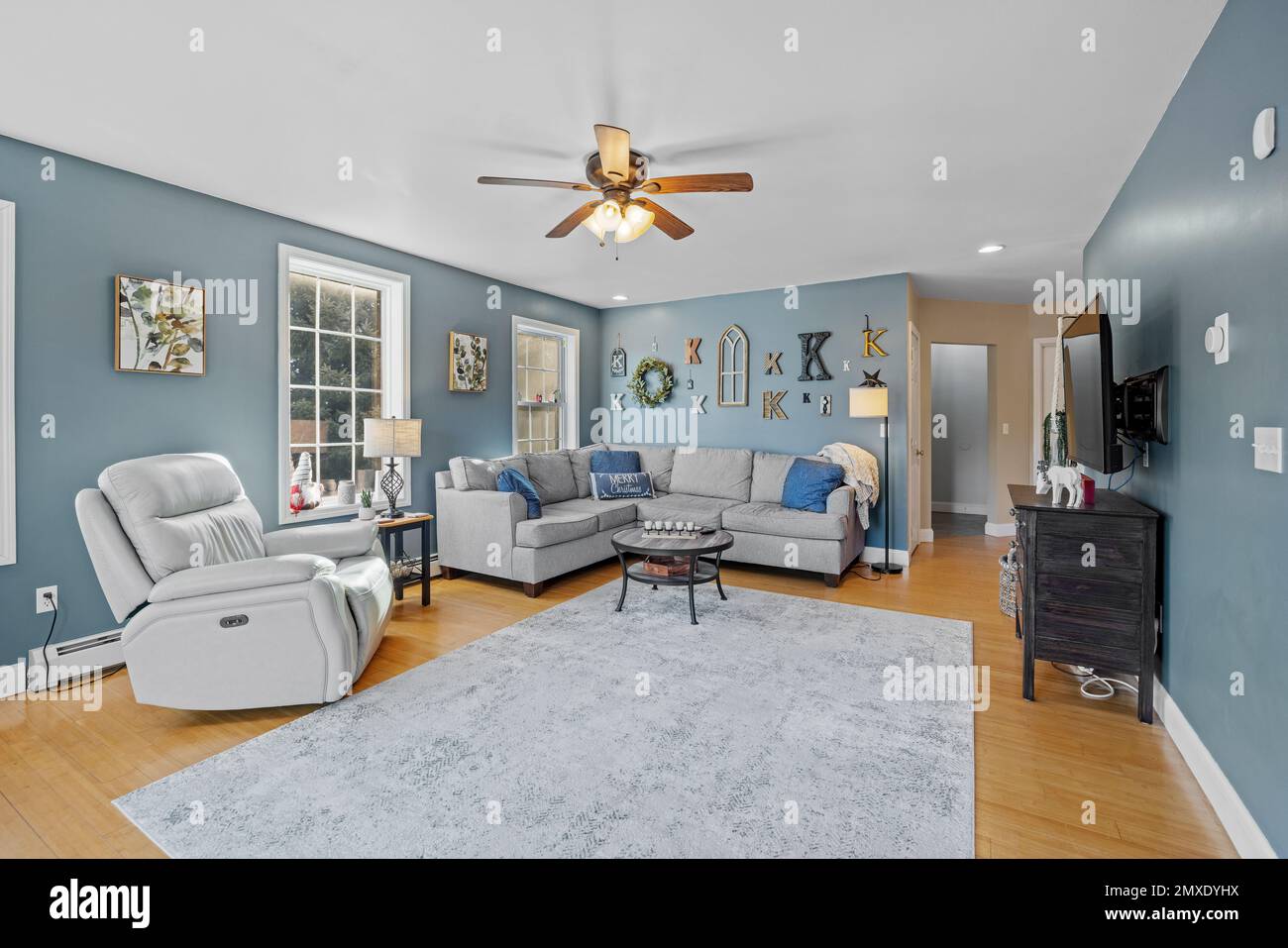 Une belle maison de banlieue intérieure avec des murs bleus et des canapés sous un ventilateur de plafond Banque D'Images