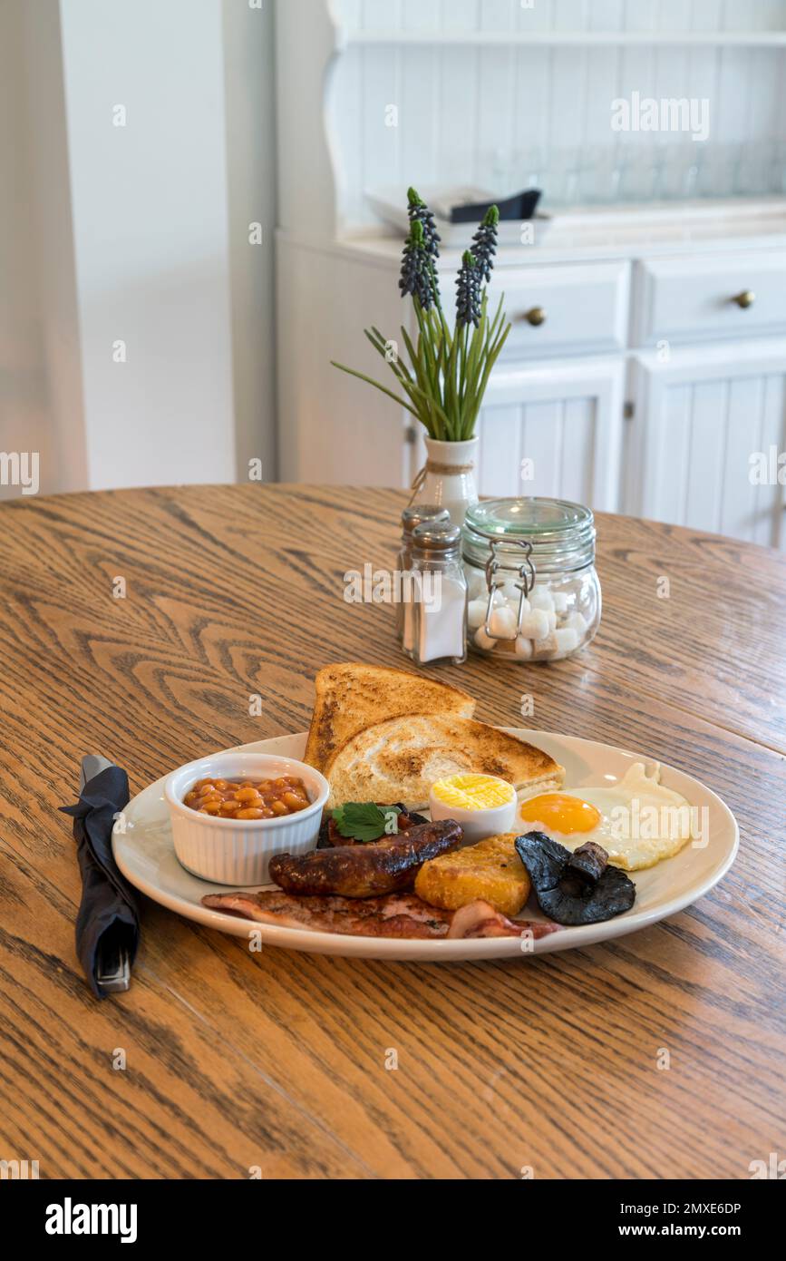 Vue intérieure d'un café lumineux et aéré avec table en bois. Petit déjeuner anglais complet sur la table - point de vue Banque D'Images