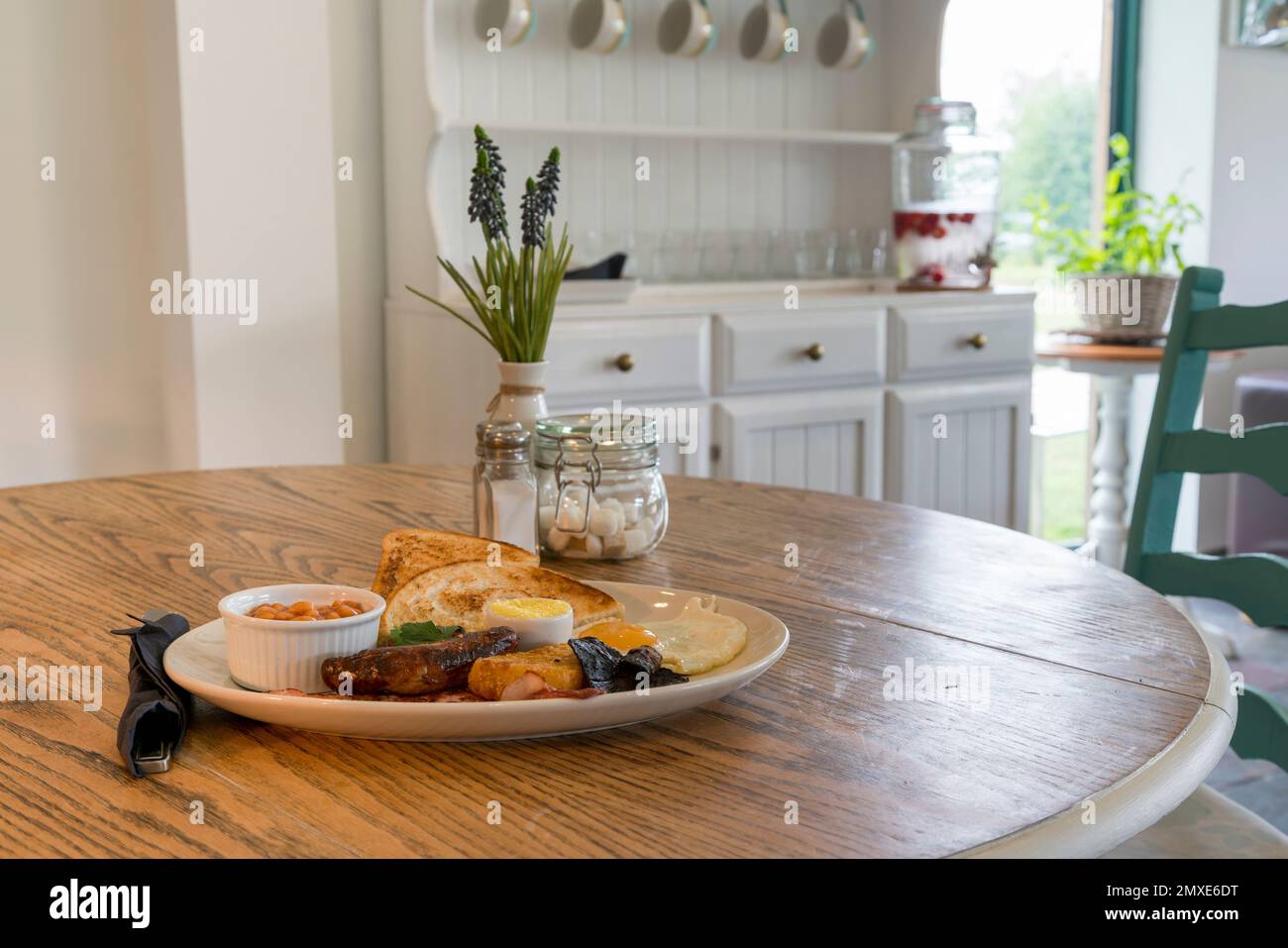 Vue intérieure d'un café lumineux et aéré avec table en bois. Petit déjeuner anglais complet sur la table - point de vue Banque D'Images