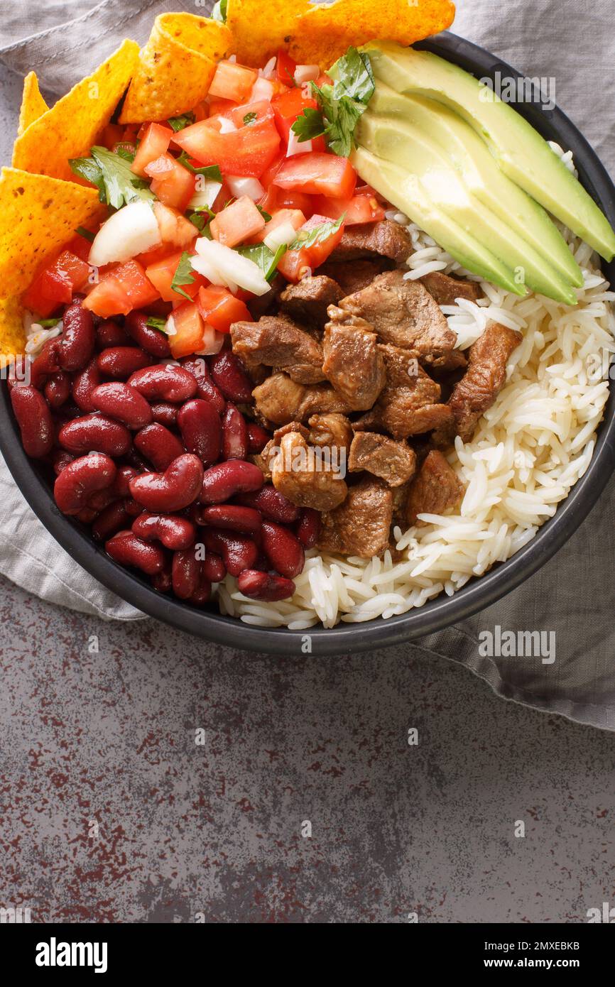 Chifrijo Costa Rica porc croustillant, riz et haricots gros plan sur l'assiette sur la table. Vue verticale du dessus Banque D'Images