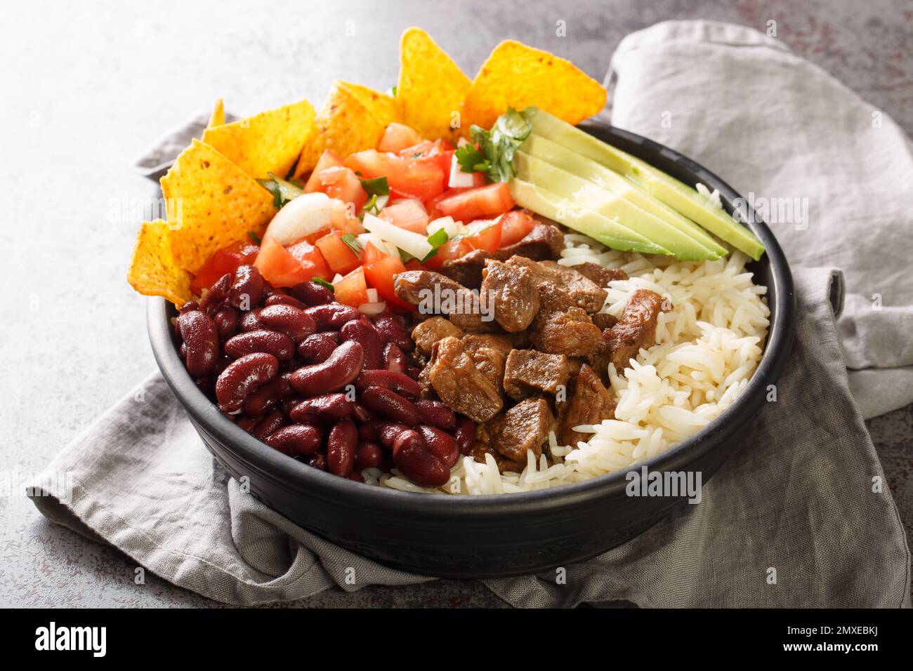 Le Chifrijo costaricain est un plat à couches de haricots tendres, garni de chicrharron et de chimichurri, servi avec des copeaux de tortilla sur l'assiette sur le t Banque D'Images