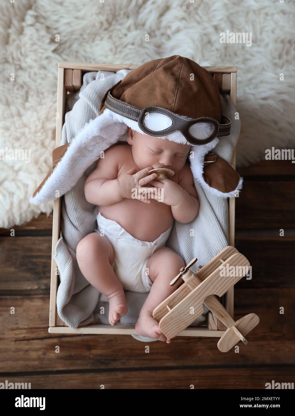Bébé mignon nouveau-né portant un chapeau aviateur avec jouet dormir dans  une caisse en bois, vue du dessus Photo Stock - Alamy