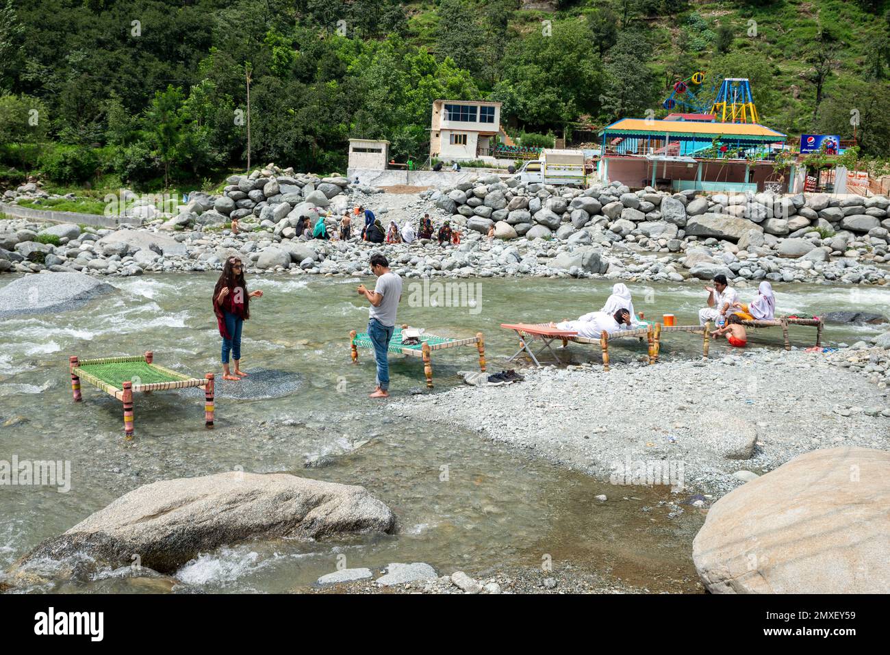 Les Pakistanais apprécient frais sur charpai (lits en bois) sur les rives de la rivière Swat en été, Swat Valley, Pakistan Banque D'Images