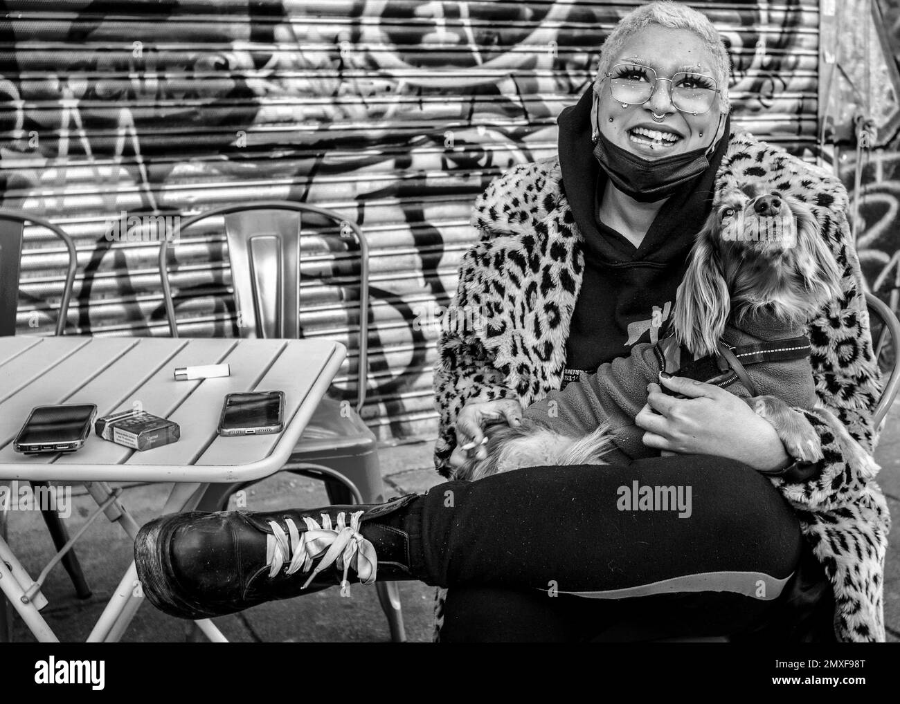 Femme négociant de rue avec cheveux roses portant le manteau d'impression de léopard, Doc Marten bottes tenant un chien, smilling dans camera.Camden marché Banque D'Images