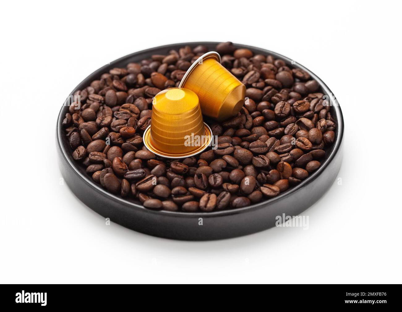 Capsules de café adaptées à la machine sur plaque ronde sur blanc avec grains de café crus. Banque D'Images