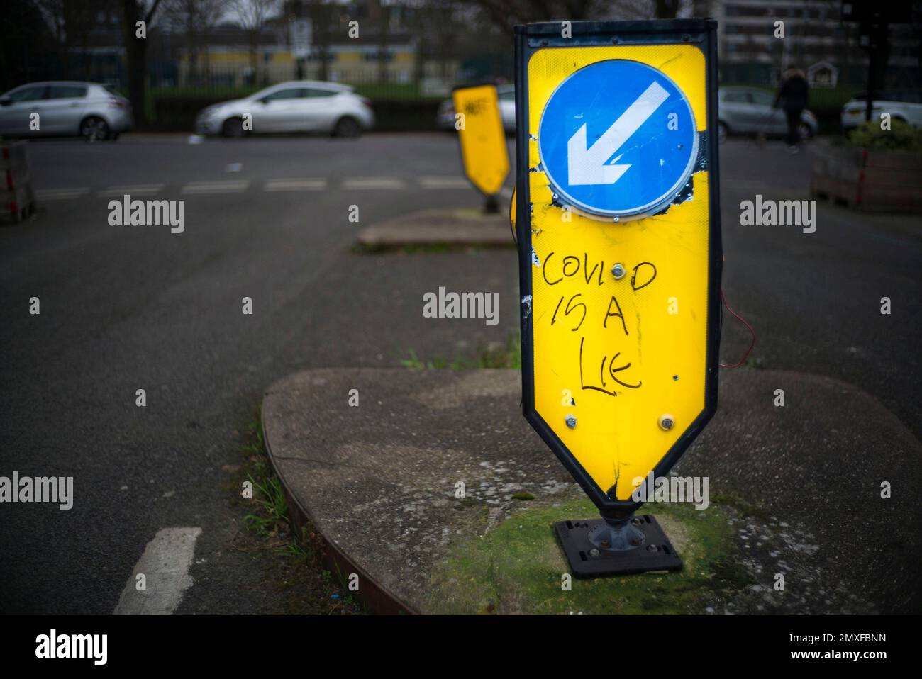 gardez la flèche blanche du panneau de gauche sur le cercle bleu sur un support jaune réfléchissant, le graffiti « covid is a lie » Banque D'Images