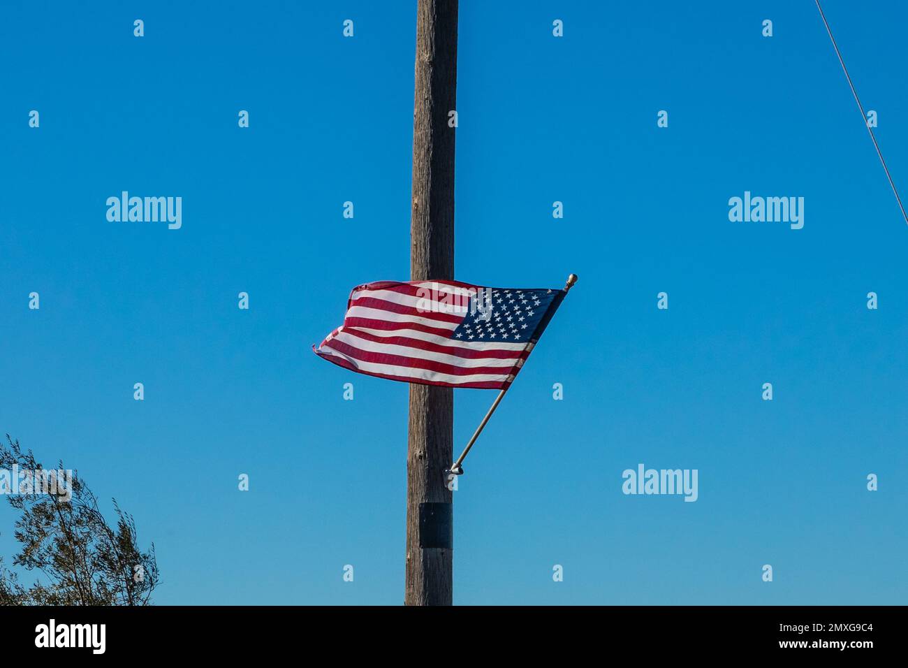 Un drapeau américain flottant dans le vent sur un poteau utilitaire dans le comté de Stanislaus Californie Etats-Unis Banque D'Images
