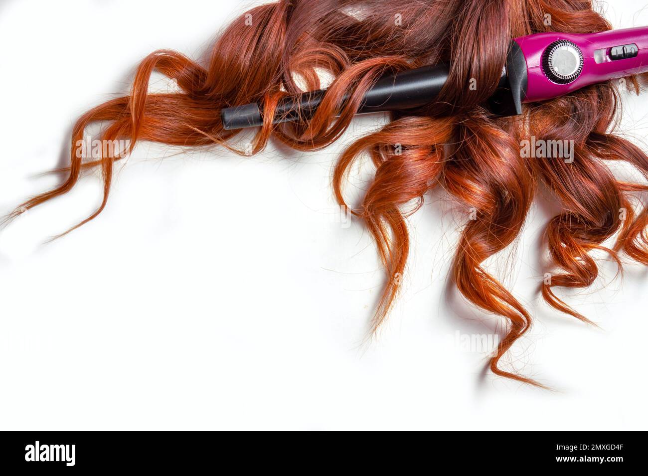 cheveux longs rouges bouclés sur fond blanc isolé avec fer à friser . Banque D'Images
