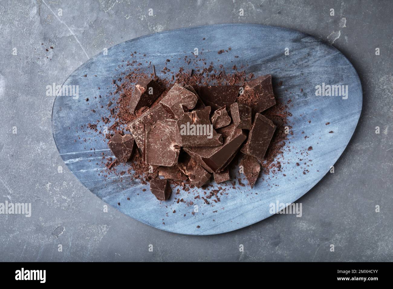 Morceaux de chocolat noir sur tableau gris, vue du dessus Banque D'Images