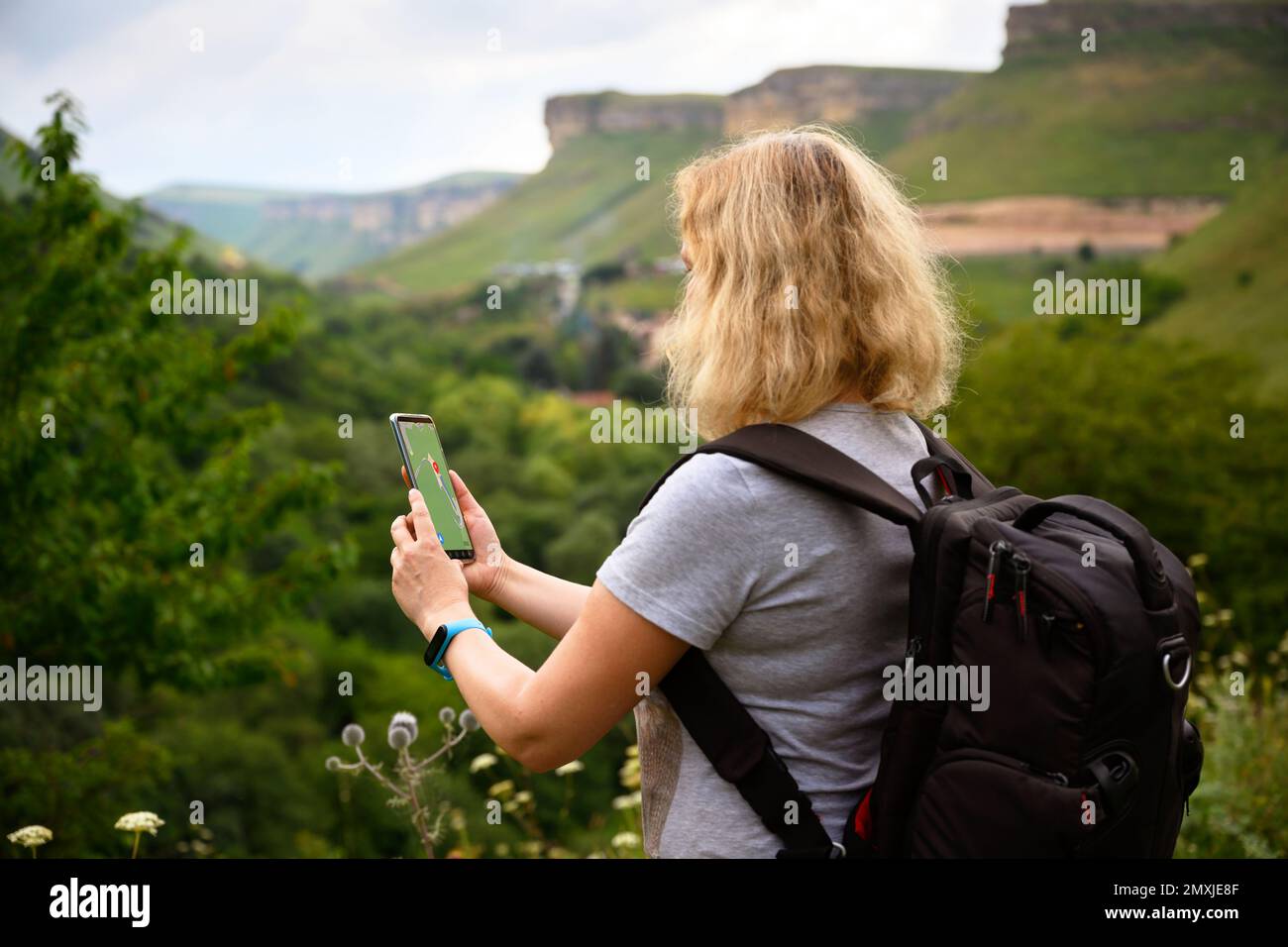 Femme randonneur utilise l'application de navigateur gps dans smartphone marchant en montagne, personne touriste regarde le téléphone mobile pour la navigation. Concept de randonnée, nature, j Banque D'Images