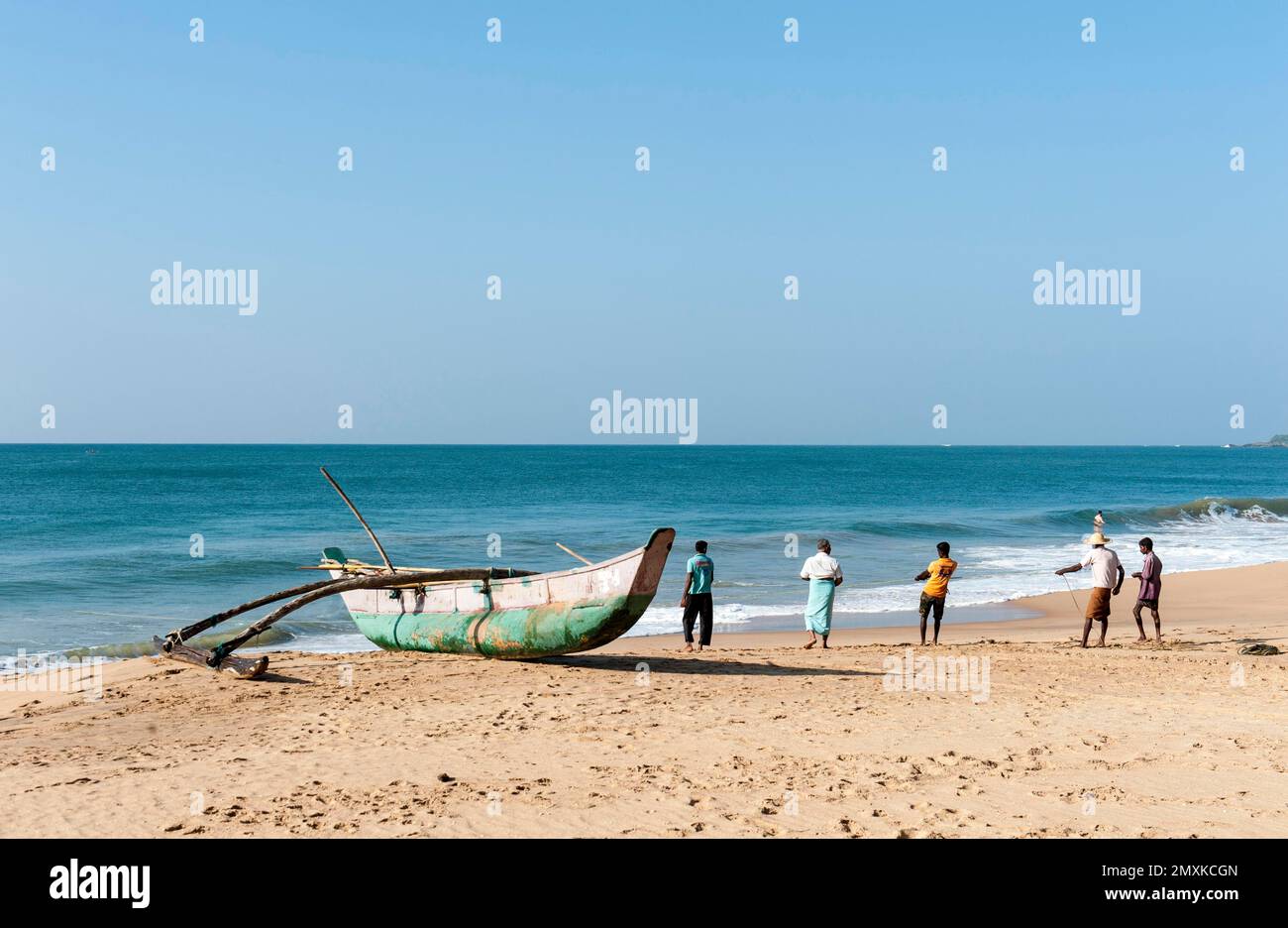 Pêcheurs au travail, les pêcheurs tirent le bateau de pêche hors de la mer sur la plage de sable, pirogue avec l'outrigger, Darwins Beach, Wella Odaya près de Ranna Banque D'Images