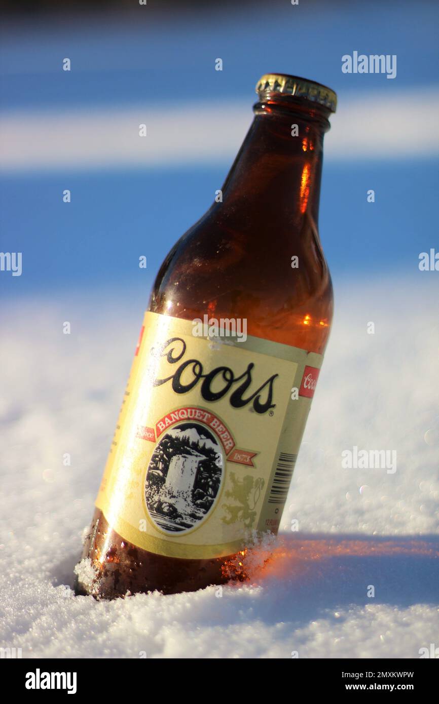 Une vieille bouteille de bière Coors réfrigérée dans la neige. Banque D'Images