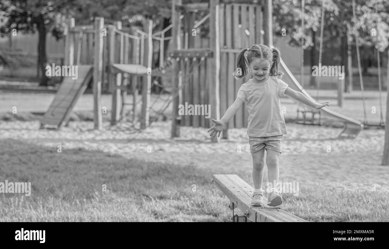 Une petite fille marche sur un terrain de jeu dans le parc Banque D'Images