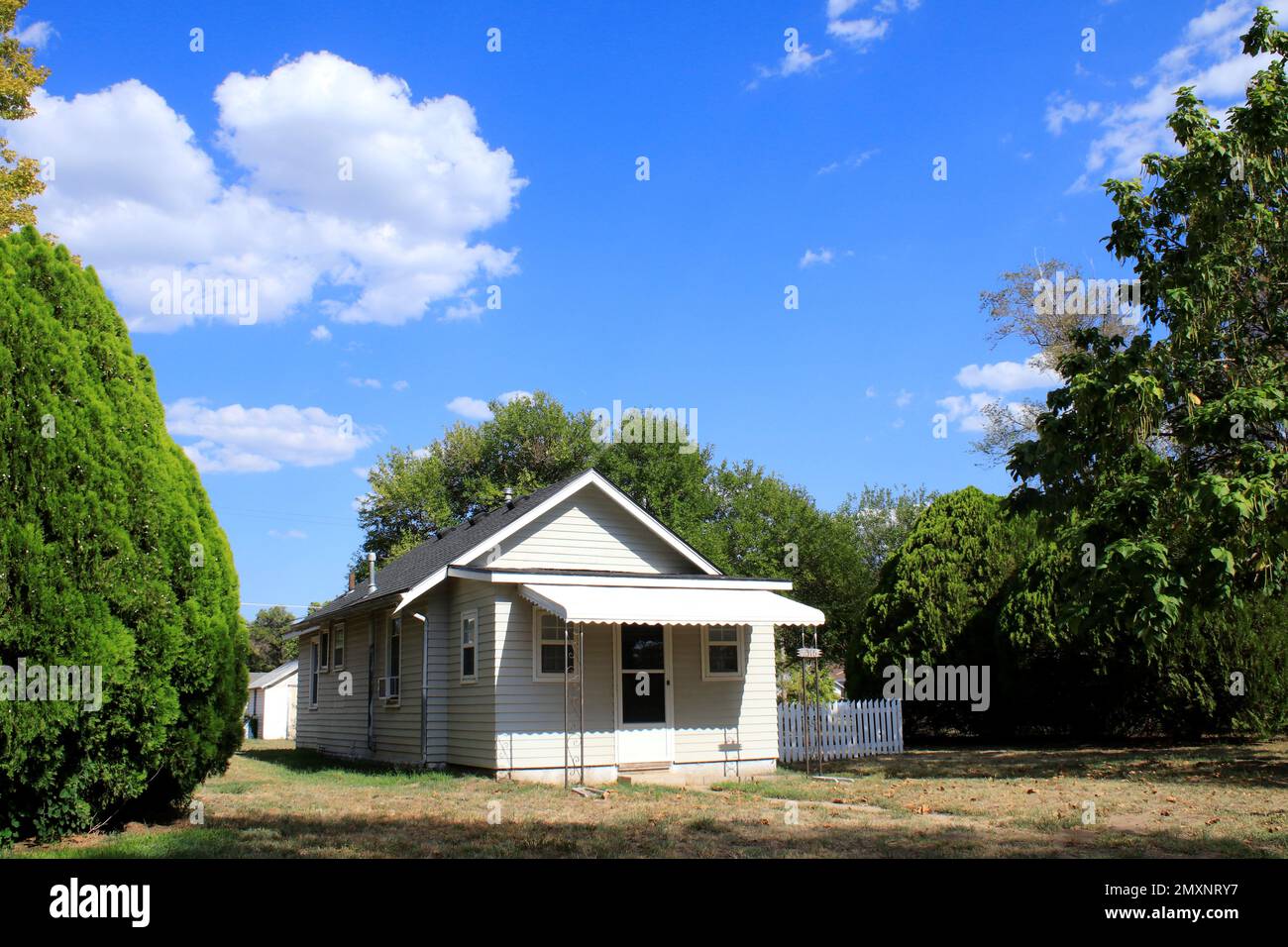 Une maison avec des nuages de ciel bleu et des arbres qui est lumineux et coloré Banque D'Images