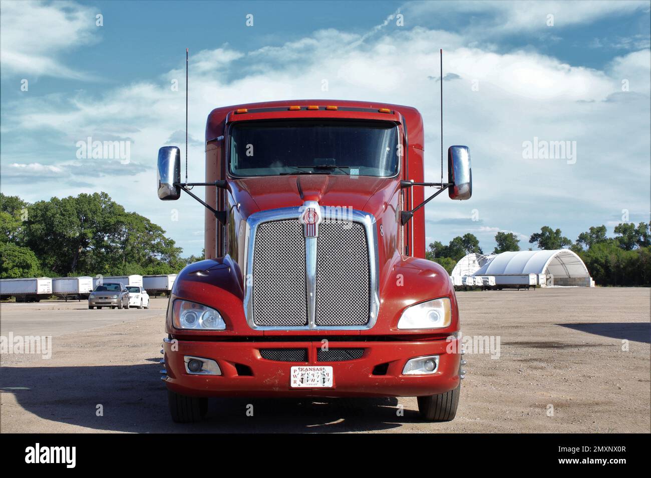 Camion Kenworth rouge dans un parking avec ciel bleu et nuages avec arbres Banque D'Images