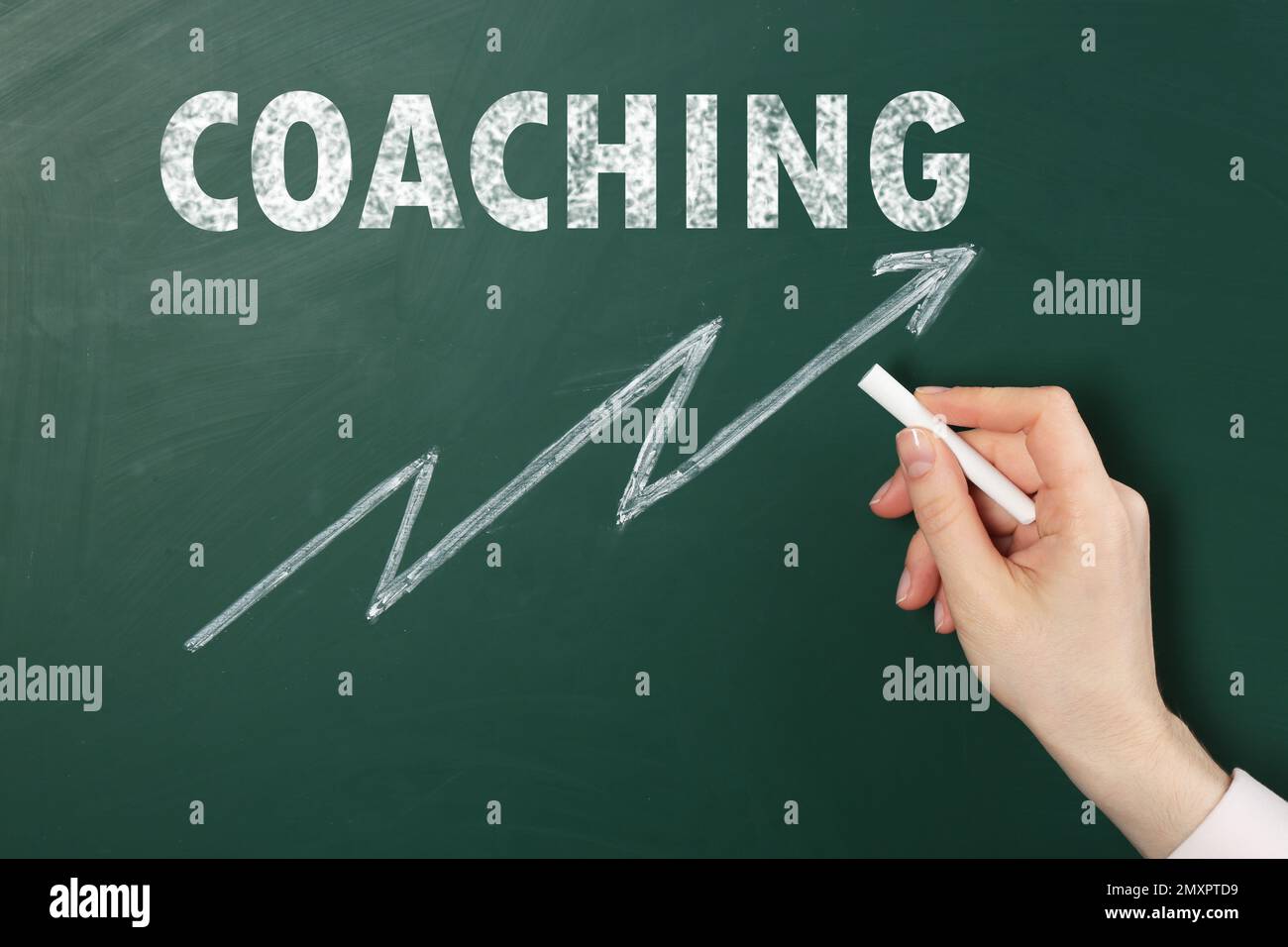 Professionnel ou entraîneur de vie dessin flèche sous le mot Coaching sur le tableau vert, gros plan Banque D'Images
