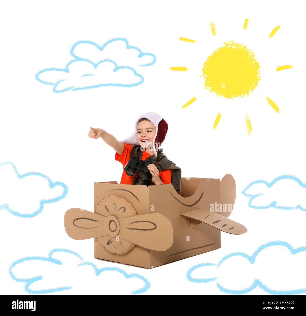Mignon petit enfant jouant dans un avion en carton sur fond blanc avec des illustrations Banque D'Images