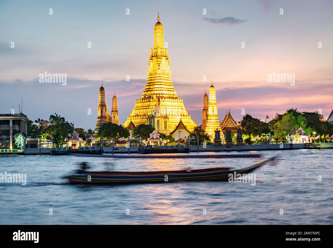 Les bateaux se déplacent le long de la rivière au crépuscule, devant le magnifique temple de l'aube illuminé d'or, lumière d'or reflétant de la surface de l'eau, Banque D'Images